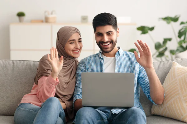 Μουσουλμάνοι Ζευγάρι Κάνοντας Βίντεο Κλήση μέσω Laptop Κυματίζοντας Χέρια Εσωτερικού — Φωτογραφία Αρχείου