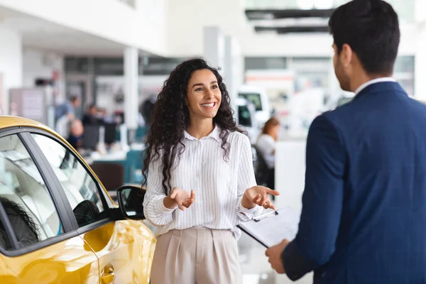 Kvinnlig kund som har samtal med säljkumpan hos bilhandlare — Stockfoto