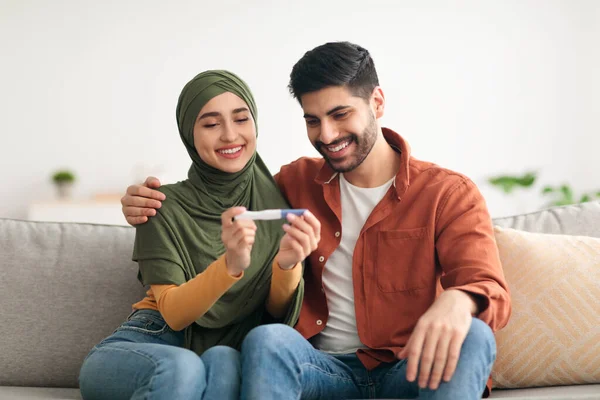 Joyful Médio Oriente casal segurando positivo teste de gravidez em casa — Fotografia de Stock