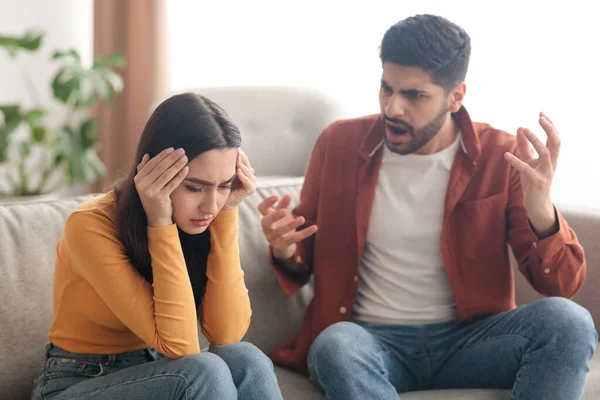 Angry Muslim Husband Yelling Wife Sitting On Sofa At Home