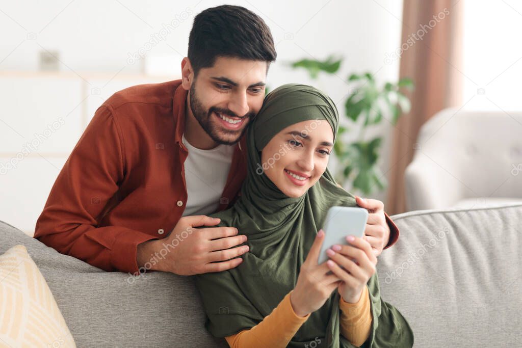 Happy Arabic Couple Using Smartphone With New Application At Home