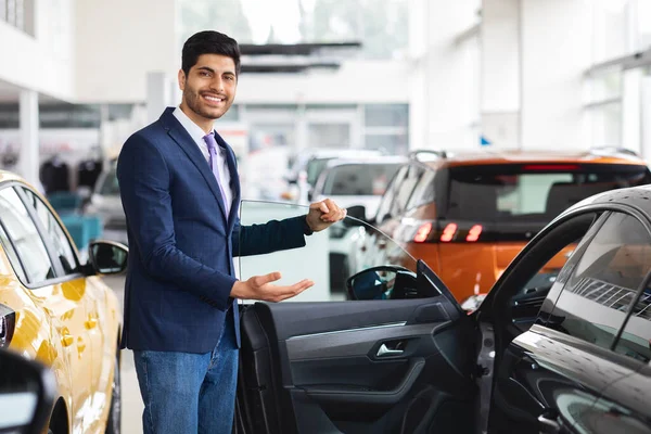 Alegre médio oriental gerente de vendas mostrando bom carro — Fotografia de Stock