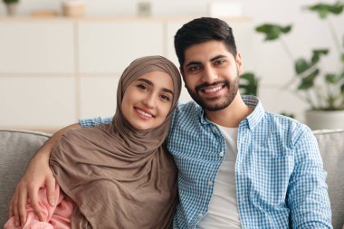 Gülümseyen Orta Doğulu çift Evdeki koltukta oturuyor