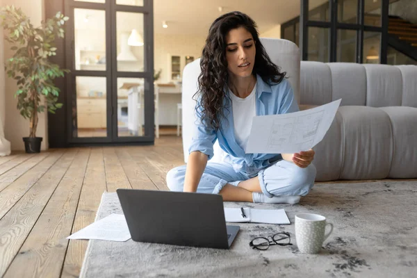 Mulher morena milenar sentada no chão com laptop e papéis, trabalhando ou estudando em casa, espaço vazio — Fotografia de Stock