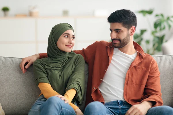 Glücklich muslimisch ehefrau wearing hijab looking at ehemann sitting drinnen — Stockfoto