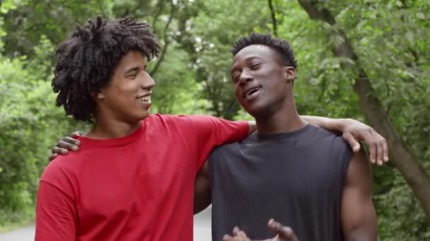 二人の黒千年の男が抱擁し、外に立って話す — ストック動画