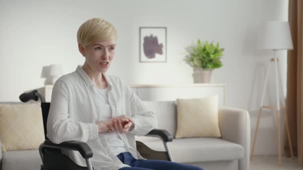 Estilo de vida positivo y discapacidad. Mujer madura feliz usuario de silla de ruedas dando entrevista, hablando a un lado con el espacio vacío — Vídeos de Stock