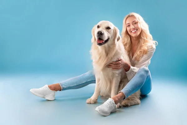 Fiatal nő pózol a kutyájával a kék stúdióban — Stock Fotó