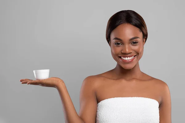 Skincare Cosmetic. Jovem sorrindo preto mulher segurando frasco com creme hidratante — Fotografia de Stock