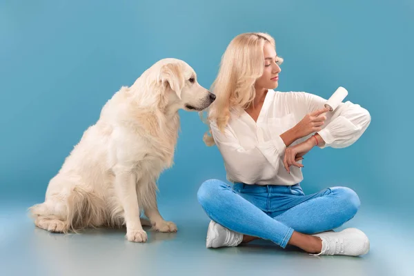 Nő tisztítja a ruháit a kutya szőrme ragasztós görgővel — Stock Fotó