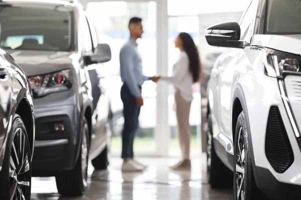 Unrecognizable man and woman shaking hands at auto showroom — Stock Photo, Image