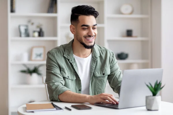 Telekommunikation. Glücklicher junger Araber arbeitet im Home Office mit Laptop — Stockfoto