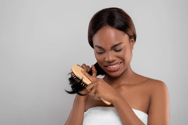 Mulher negra infeliz pentear seu cabelo enrugado com escova de bambu — Fotografia de Stock