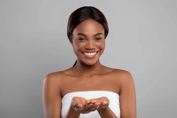 Happy Black Female Wrapped In Bath Towel Demonstrating Something On Empty Palms — Stock Photo, Image