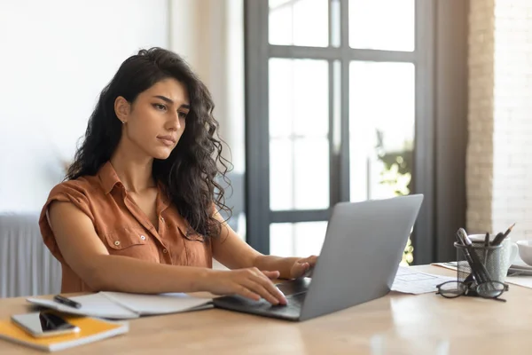 Konzentrierte junge Freelancerin arbeitet online, nutzt Laptop zu Hause, Kopierraum — Stockfoto