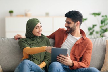 İçerideki koltukta oturan Tablet Bilgisayar kullanan neşeli Arapça eşler