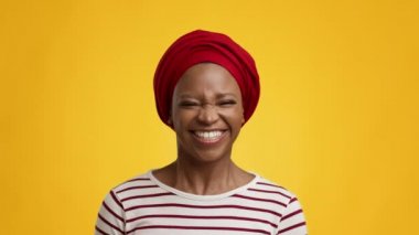 Kameraya gülümseyen Afrikalı Kadın Kırmızı Başlıklı, Sarı Arkaplan