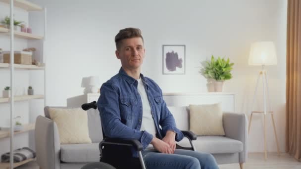 Portrait intérieur d'un homme d'âge moyen serein avec un handicap assis en fauteuil roulant et regardant la caméra à la maison — Video