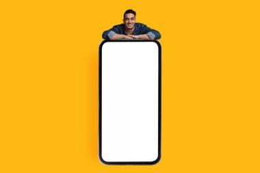 Yakışıklı Arap adam boş ekranlı akıllı telefona yaslanıyor.