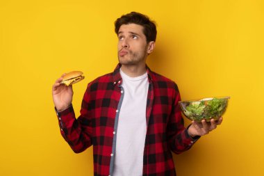 Hamburger ve salata tutan komik adamın portresi.