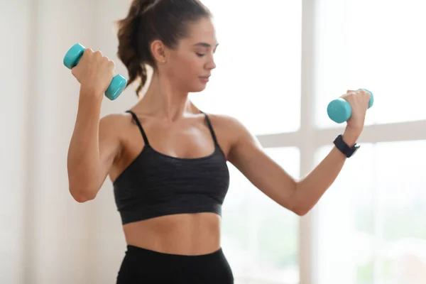 Sportig dam tränar med två hantlar på gym — Stockfoto