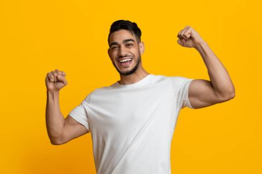 Neşeli atletik orta doğulu adam kaslarını gösteriyor