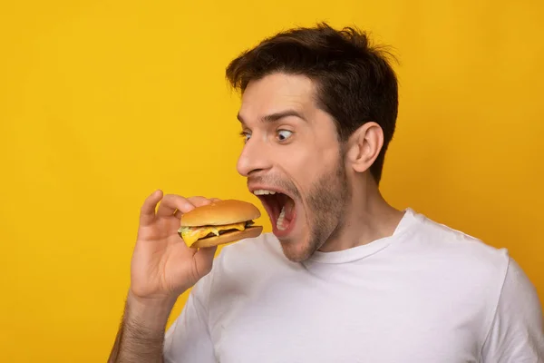 Funny Guy držení Burger kousání sendvič v ateliéru — Stock fotografie