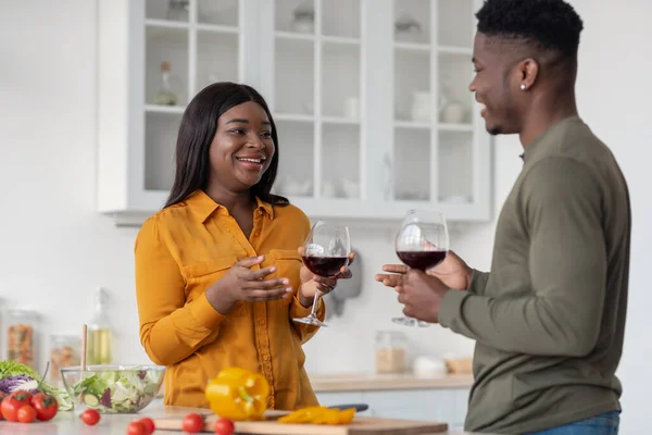 Portrait de heureux couple noir bavarder et boire du vin rouge dans la cuisine — Photo