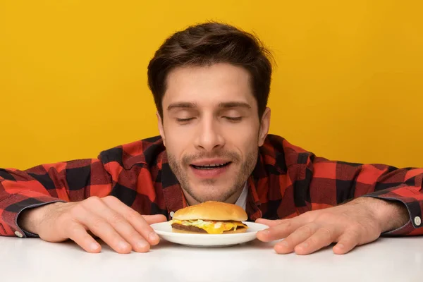 Closeup de cara animado Smelling saboroso hambúrguer no estúdio — Fotografia de Stock