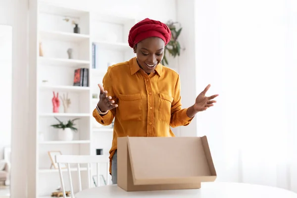 Aufgeregte schwarze Dame öffnet Lieferbox zu Hause — Stockfoto