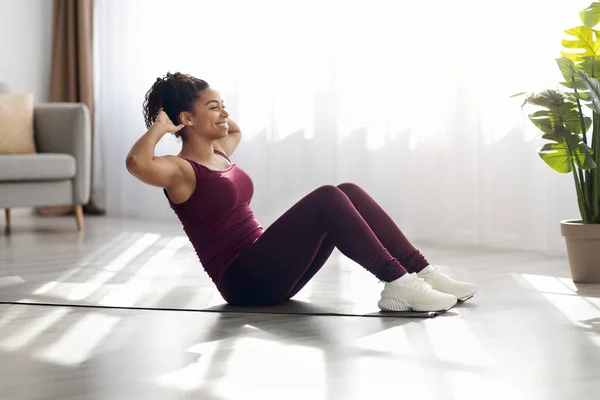Fröhliche Afroamerikanerin trainiert zu Hause auf Fitnessmatte — Stockfoto