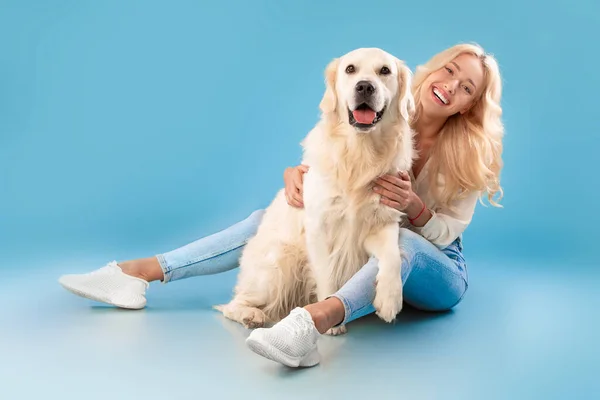 Fiatal nő ül a kutyájával a kék stúdióban — Stock Fotó