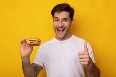 Burger tutan komik adam Başparmağını kaldırıyor.