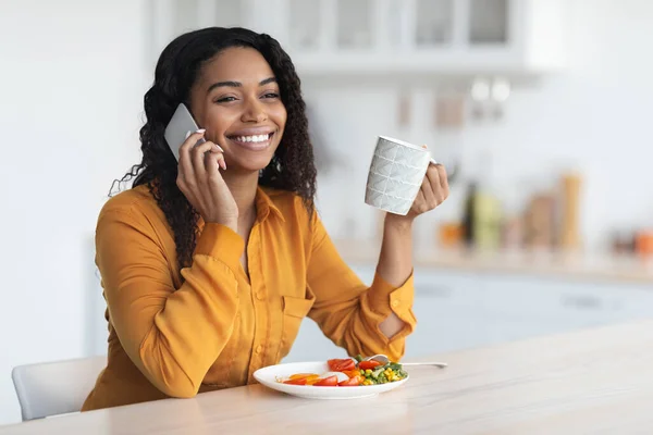 Ontspannen Afrikaans-Amerikaanse dame ontbijten, telefonisch praten — Stockfoto