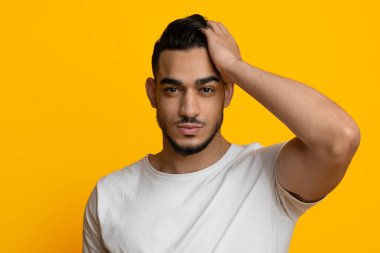 Sarı stüdyo arka planında poz veren seksi ortadoğulu adam.