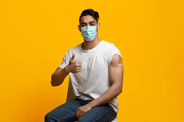 Muž s obličejovou maskou ukazující lékařskou pásku na rameni — Stock fotografie