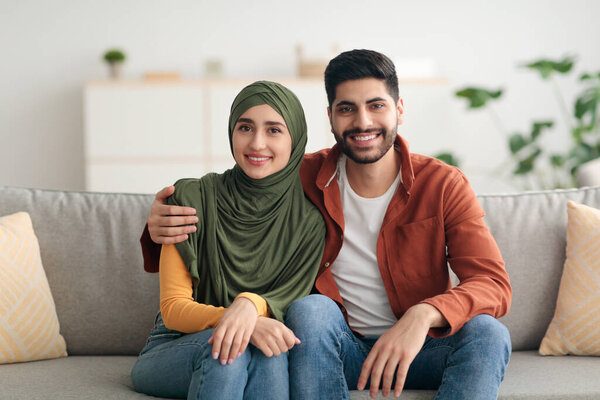 Middle Eastern Couple With Wife Wearing Hijab Embracing At Home
