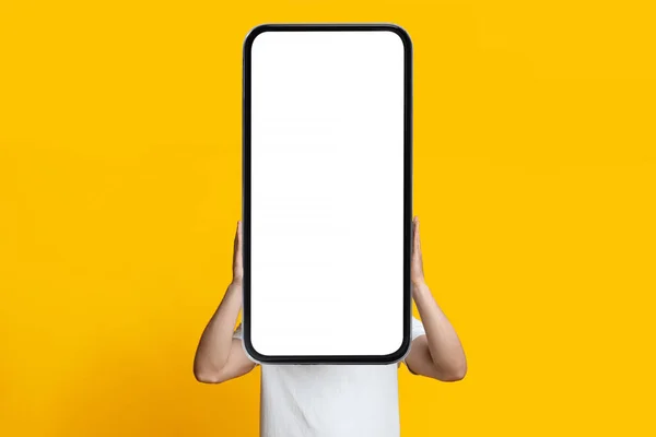 Nerozpoznatelný chlap skrývající se za smartphonem s prázdnou obrazovkou — Stock fotografie