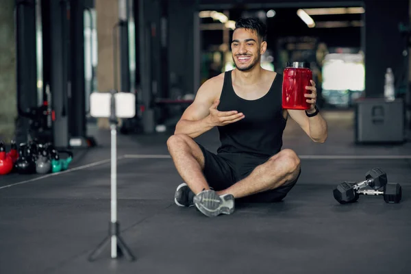 Homem árabe sorridente recomendando suplementos de fitness para musculação em seu Fitness Blog — Fotografia de Stock