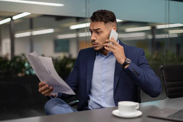 Wütender arabischer Geschäftsmann liest Dokumente und telefoniert — Stockfoto
