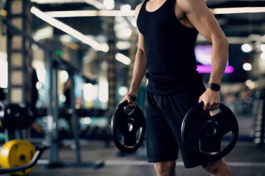 Spor salonunda antrenman yaparken halter kaldıran kaslı adamın portresi