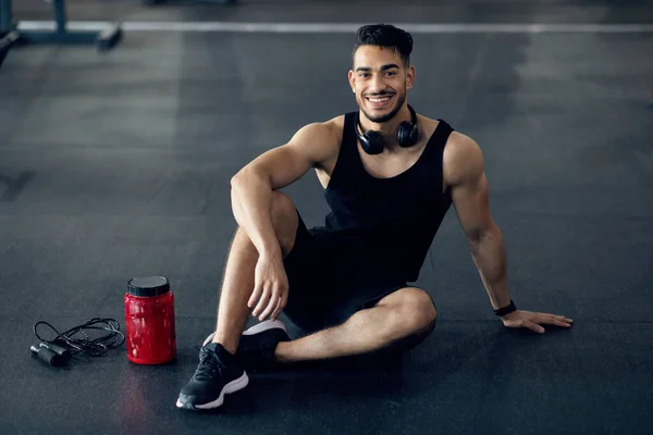 Schöne arabische männliche Athletin entspannt sich nach dem Training im Fitnessstudio auf dem Boden — Stockfoto