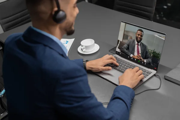 Homme d'affaires ayant une vidéoconférence avec un partenaire d'affaires noir — Photo