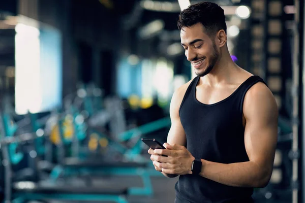 Bello giovane mediorientale uomo utilizzando Smartphone durante l'allenamento in Sport Club — Foto Stock