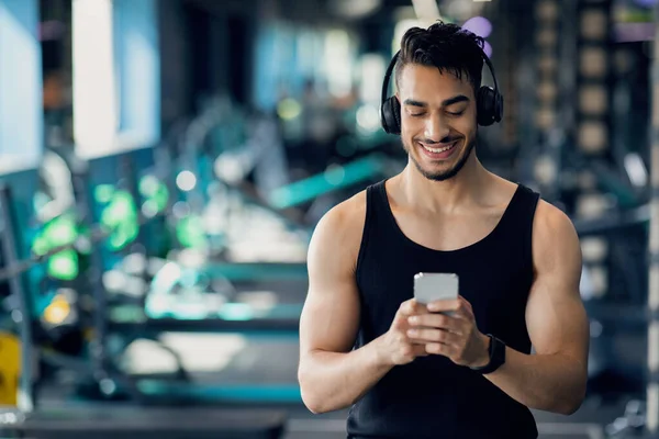 Felice giovane arabo uomo messaggistica su smartphone mentre si rilassa dopo l'allenamento di sport — Foto Stock