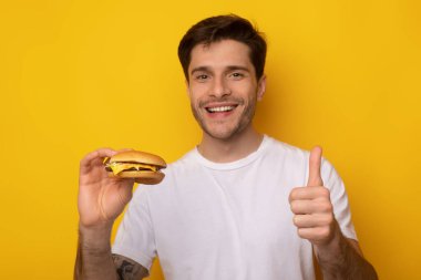 Burger tutan komik adam Başparmağını kaldırıyor.