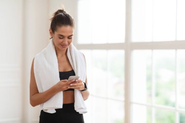 Antrenman molasında telefonu kullanan fitness kadını.