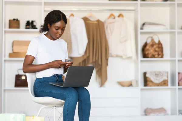 Mulher negra grave usando Smartphone e Laptop Compras em casa — Fotografia de Stock