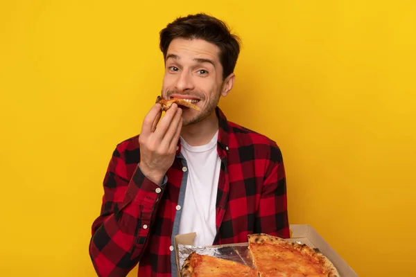 Happy Guy segurando caixa mordendo pizza no estúdio de laranja — Fotografia de Stock