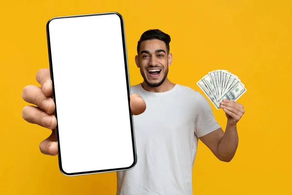 Emocional cara do Oriente Médio mostrando tela em branco smartphone e dinheiro — Fotografia de Stock